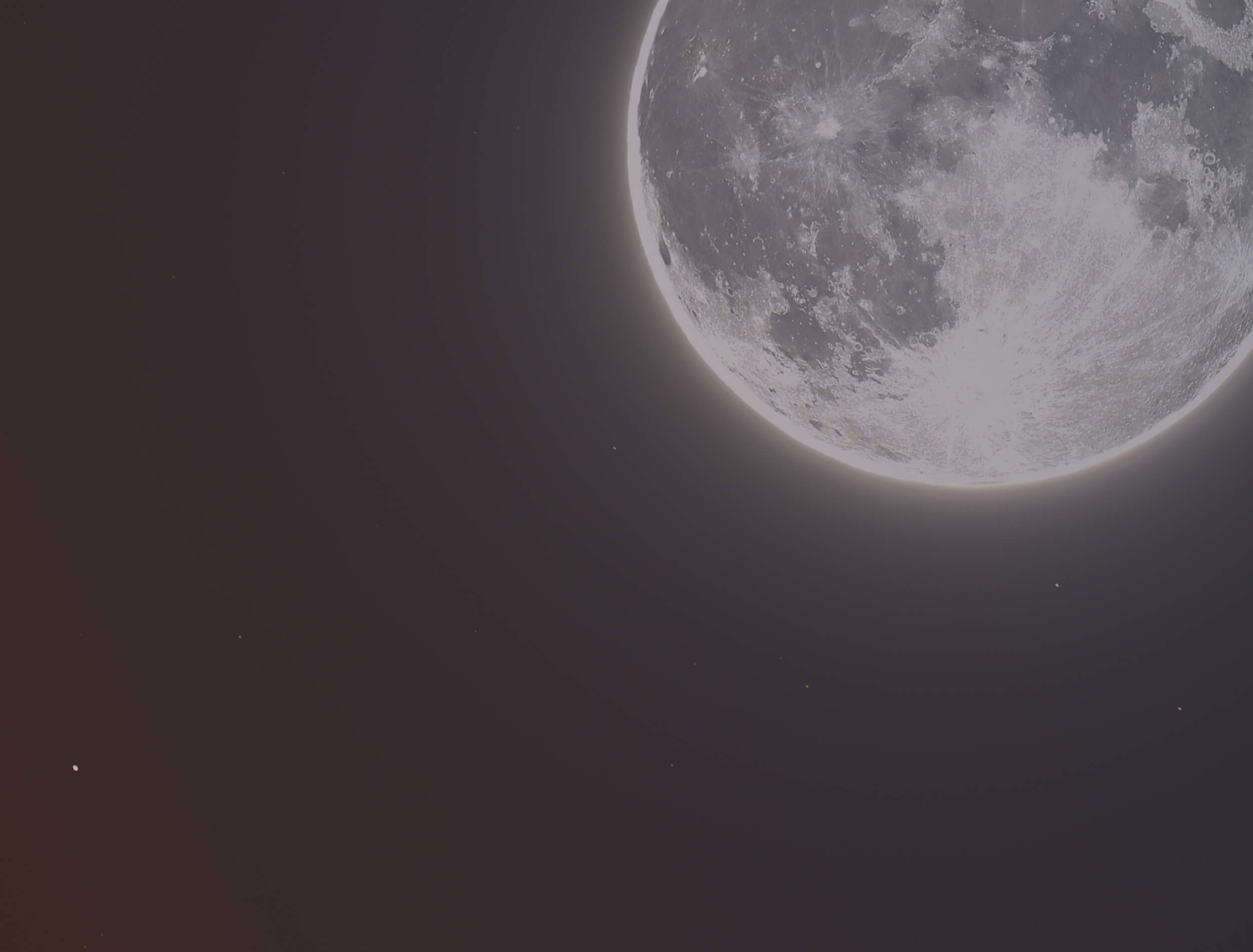 Luna piena luminosa nell’angolo superiore destro del cielo notturno, con crateri e dettagli della superficie ben visibili su sfondo scuro punteggiato di stelle.