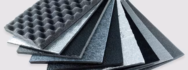 Serie di pannelli isolanti impilati con superfici differenti, tra cui schiuma bugnata e rivestimenti riflettenti.